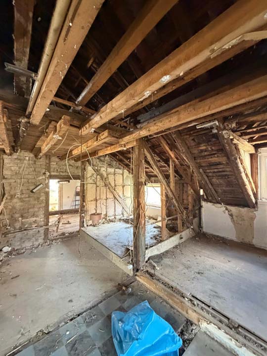 Dachgeschoss während der Kernsanierung mit freigelegten Holzbalken und geöffneten Wandbereichen