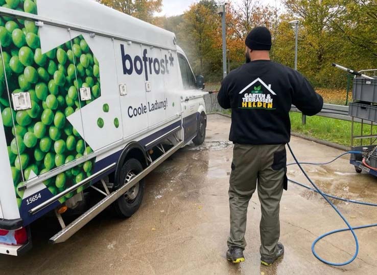 Mitarbeiter bei der Hochdruckreinigung neben einem Lieferwagen