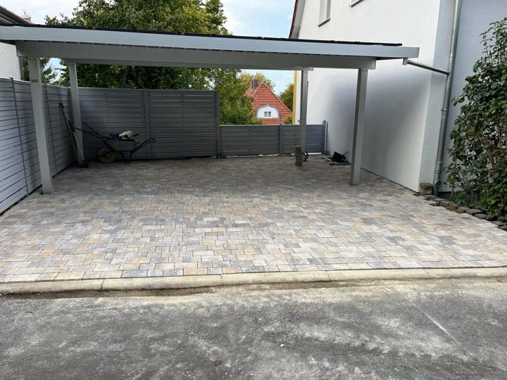 Gepflasterte Fläche unter einem Carport neben einem Wohnhaus
