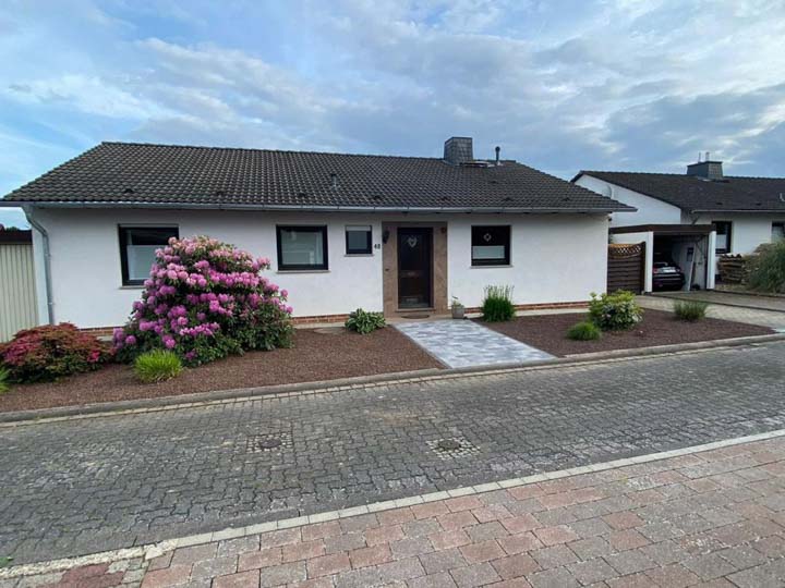 Neu gestalteter Vorgarten mit bepflanzten Kiesflächen und Natursteinweg vor einem Wohnhaus